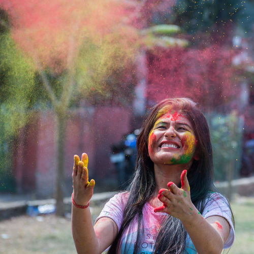 Close-up of smiling young woman playing holi