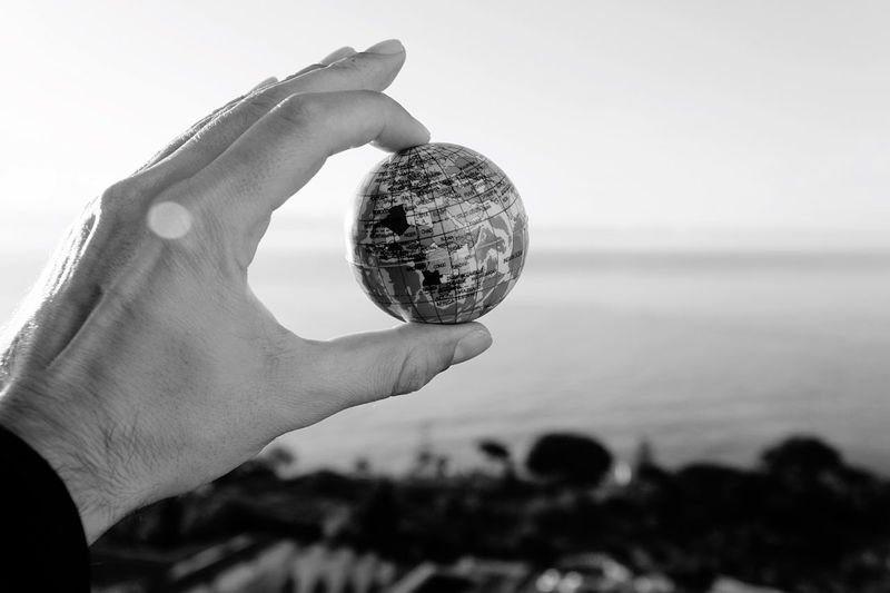Close-up of hand holding globe against sky