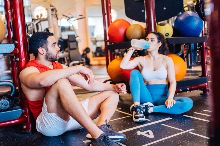 Portrait of couple in love at gym watching exercise on mobile phone stopped to drink water