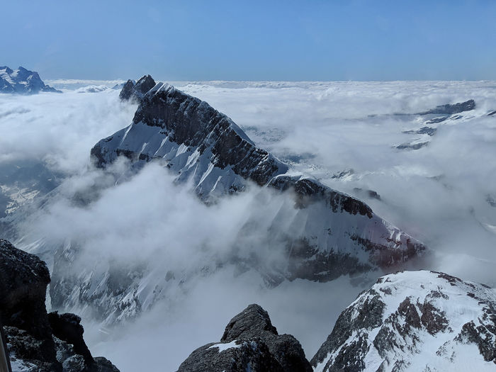 Panoramic view of snowcapped mountains covered in clouds against sky