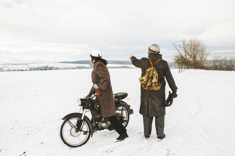People riding motorcycle on snow covered land