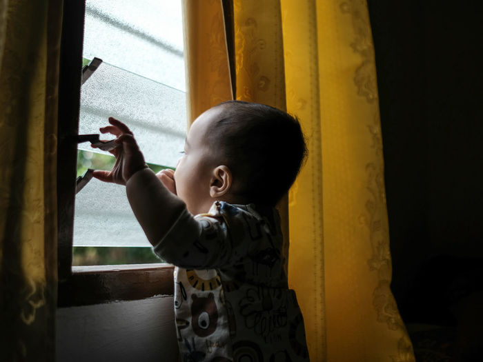 Portrait of a toddler looking through a window