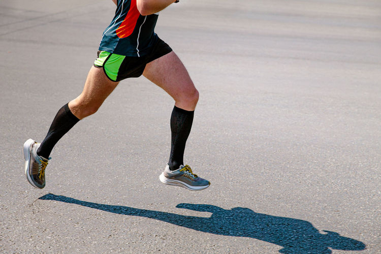 Legs male runner in black compression socks run road
