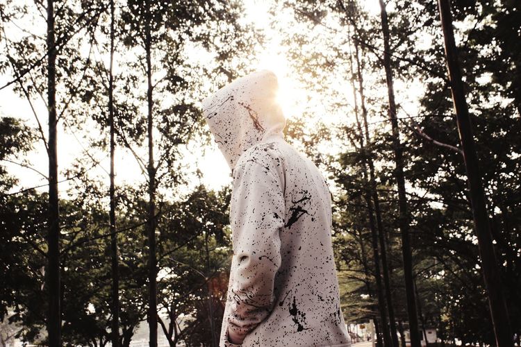 Side view of person in hood standing in forest