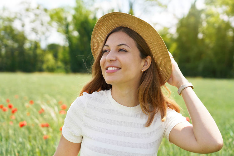 Portrait of smiling young woman wearing hat on field
