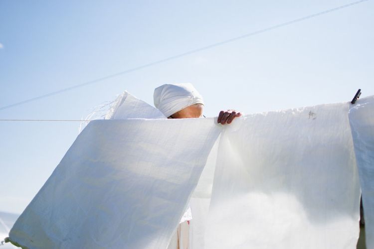 Senior woman behind white clothes drying