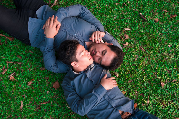High angle view of gay couple sleeping on field