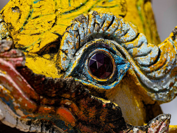Colorful yellow stone sculpture of mythical creature eye close up in thai temple in chiang mai