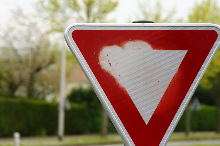 Close-up of yield sign on street against trees
