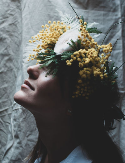 Close-up of woman with flowering plant on face