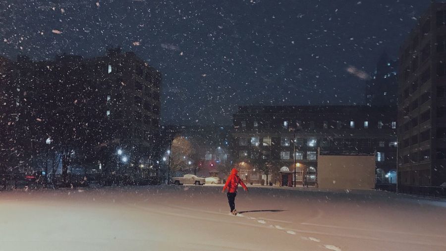 Man on snow in city against sky at night