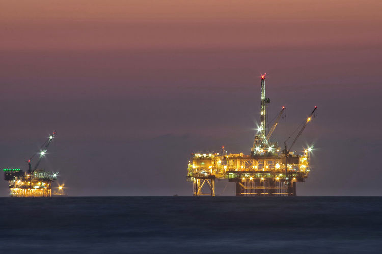 Illuminated commercial dock by sea against sky at night
