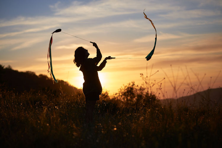 Woman juggling at sunset. she's in a nice meadow in the country.