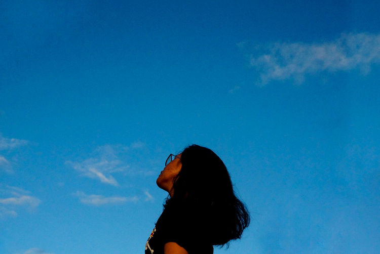 Young woman against blue sky