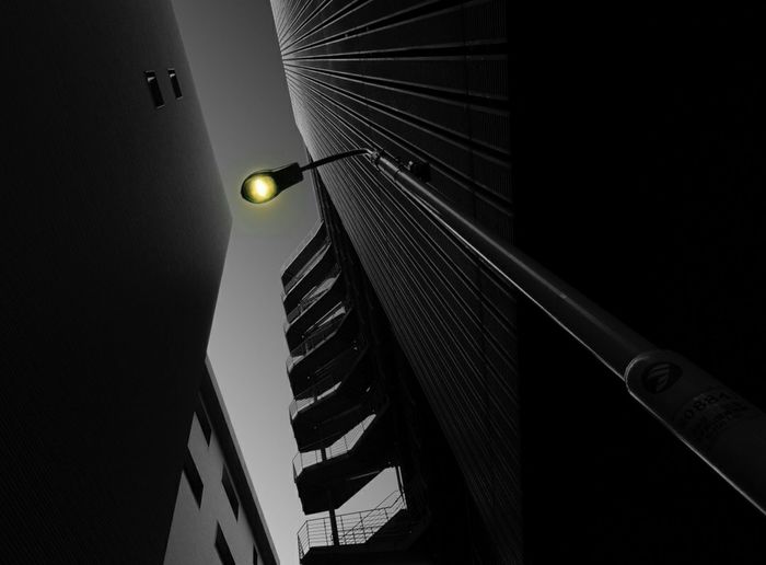 Low angle view of illuminated lamp on building at night