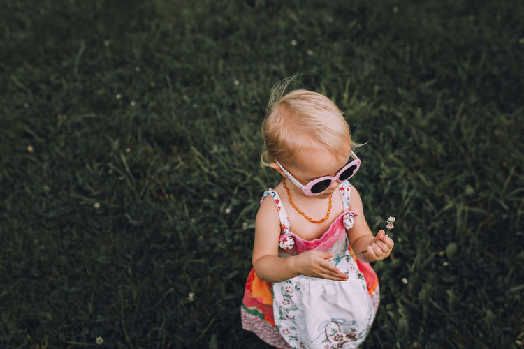 Girl wearing sunglasses while holding flower on grass