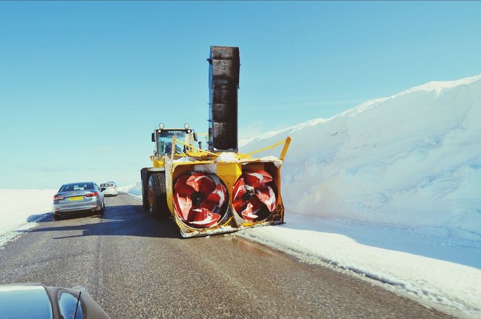 Snowblower on road against clear blue sky