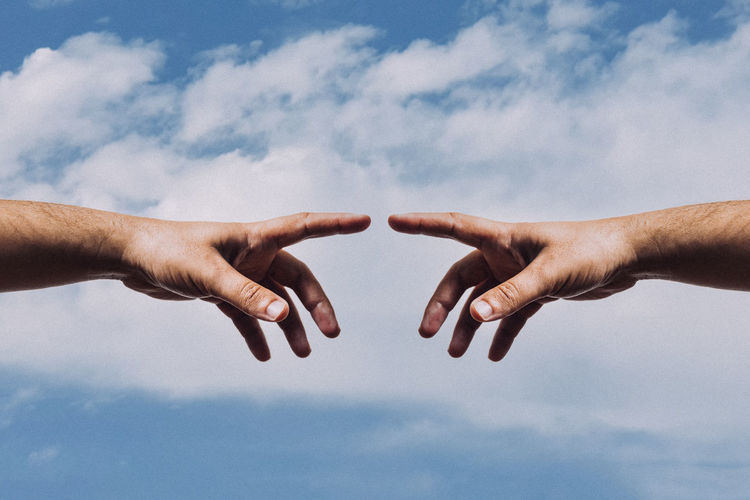 Show hand of man with forefinger reach for point and touch against sky - connection