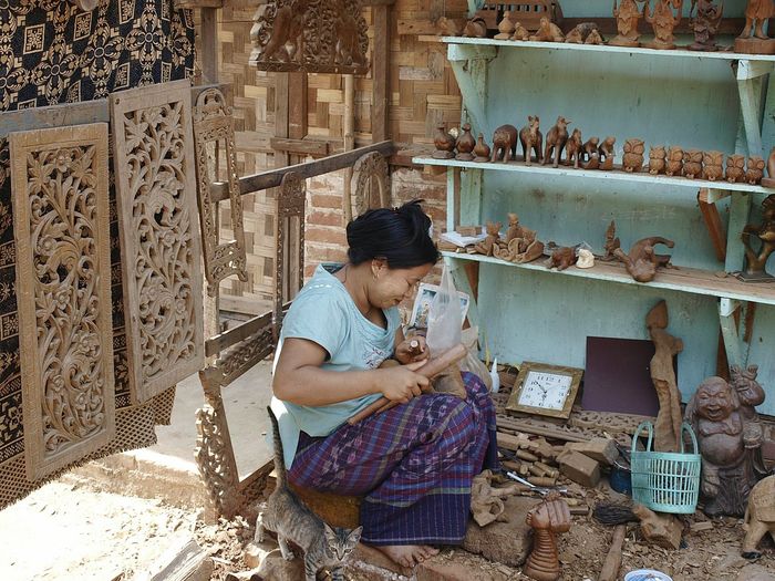 Woman craving wood while sitting at market