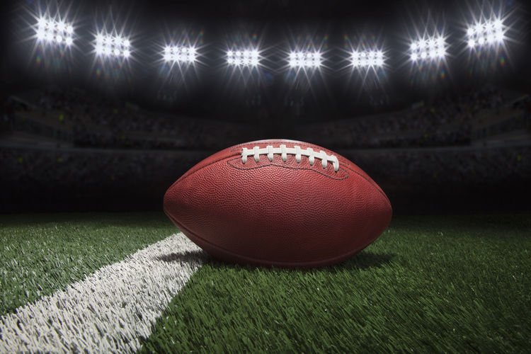 Close-up of american football on field at night