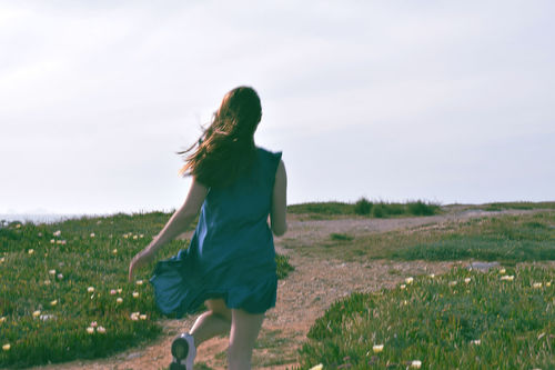 Woman running on field against sky