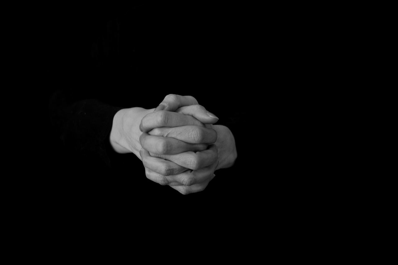 CLOSE-UP OF HAND HOLDING BLACK BACKGROUND