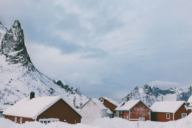 Houses by snow covered mountains against sky