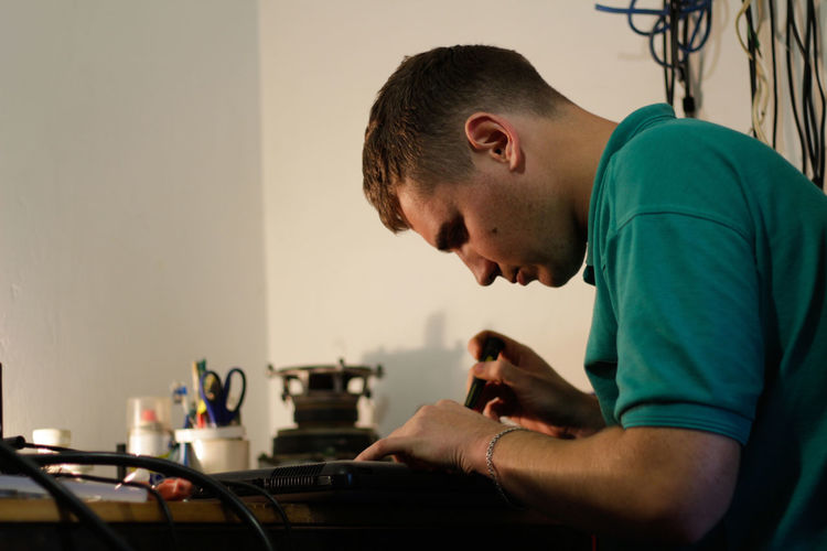 Young man, engineer soldering black laptop. electronic renovation in repair service. worker check