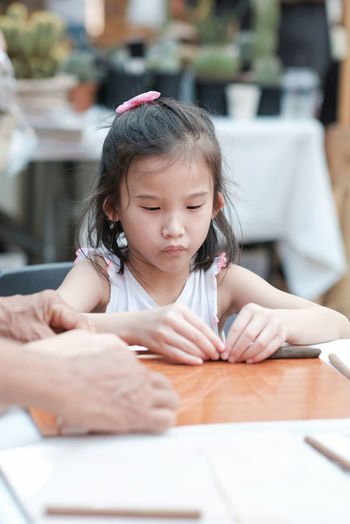 Cute girl sitting by table at sidewalk cafe