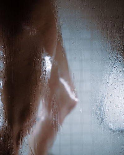 Person seen through wet glass window in rainy season