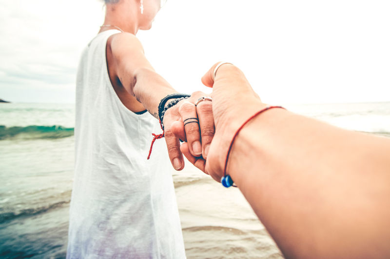 Midsection of woman holding hands on beach