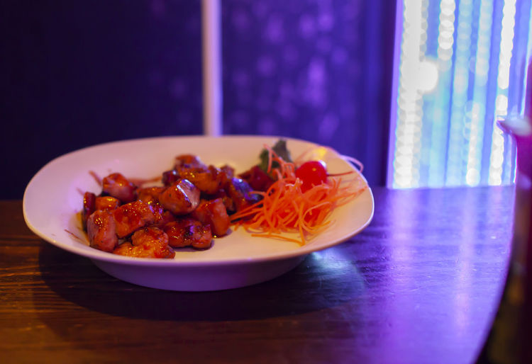 Grilled shrimp and chicken and shredded carrots on a white serving plate
