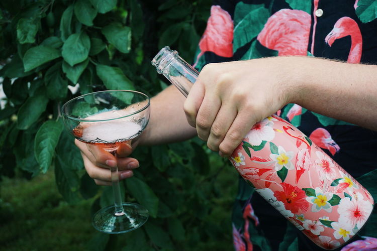 Young man serving rosé wine at a garden party
