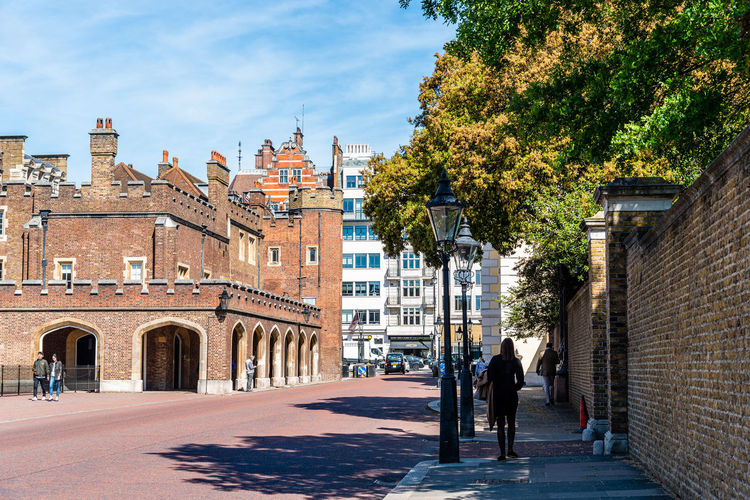 People walking by marlborough road in front of st james palace in westminster a sunny day 