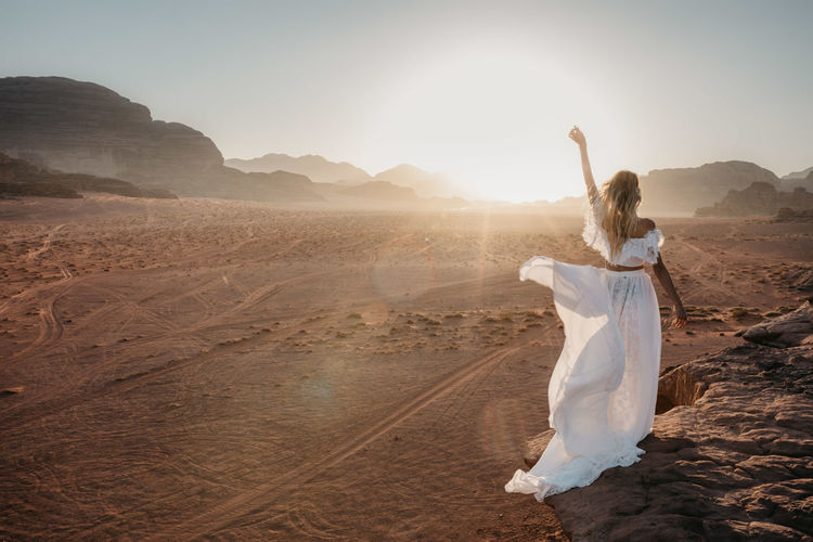 Woman in dress standing on landscape against sky