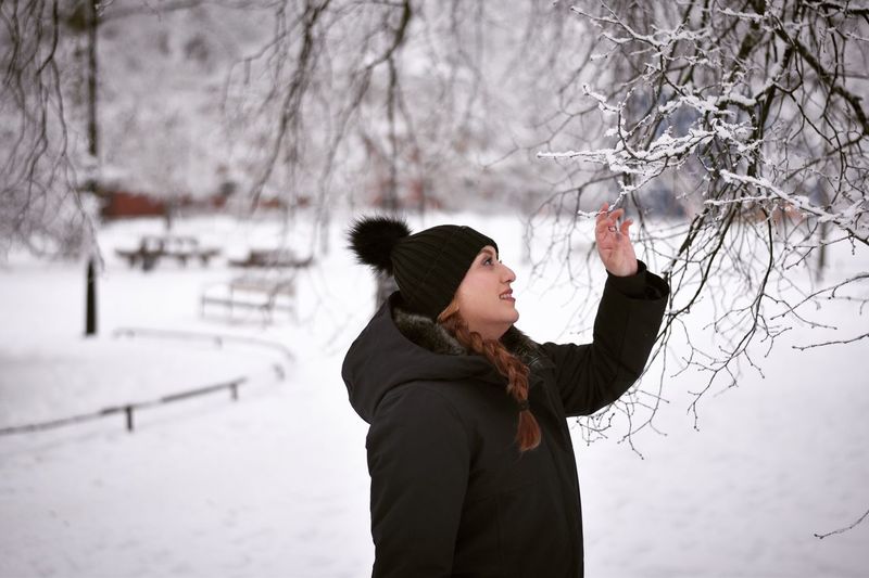 Woman looking at branch during winter