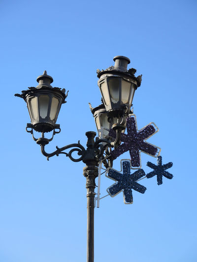 Low angle view of christmas street decoration against blue sky