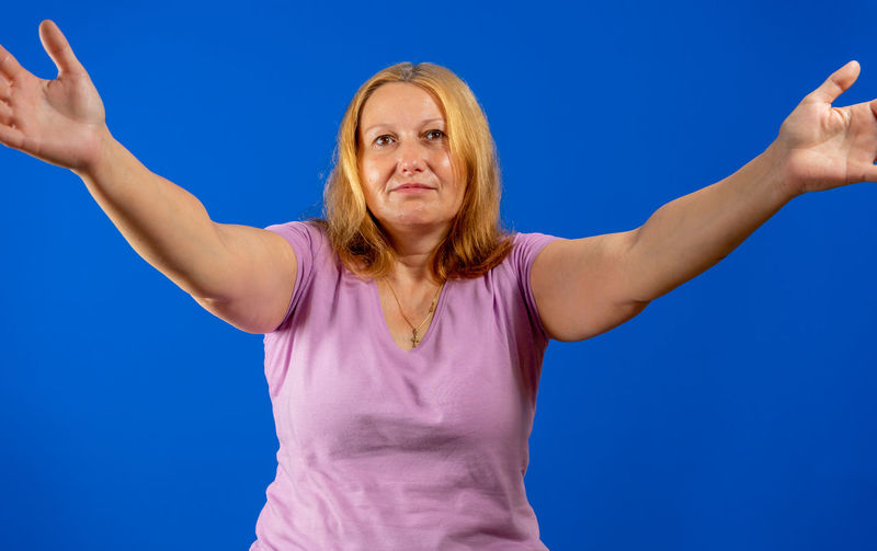 Low angle view of woman standing against blue background