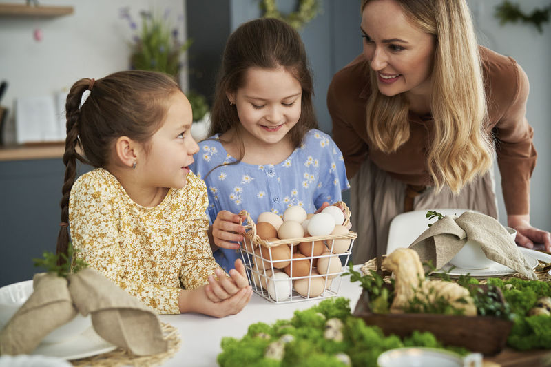 Smiling mother talking with daughters in kitchen