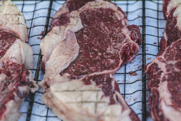 Fresh meat on barbecue metal mesh grilling basket rack. raw beef steak. 