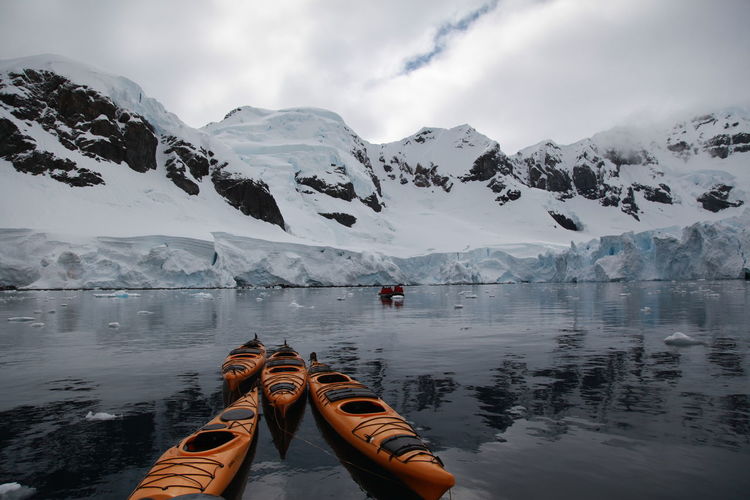 Kayaks in lake against snowcapped mountains