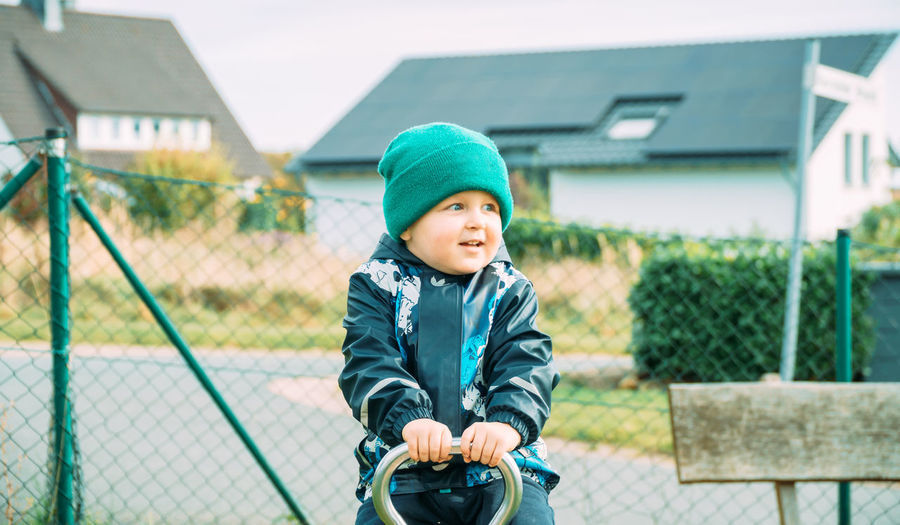Little boy dressed in warm clothes playing on the playground on an autumn day