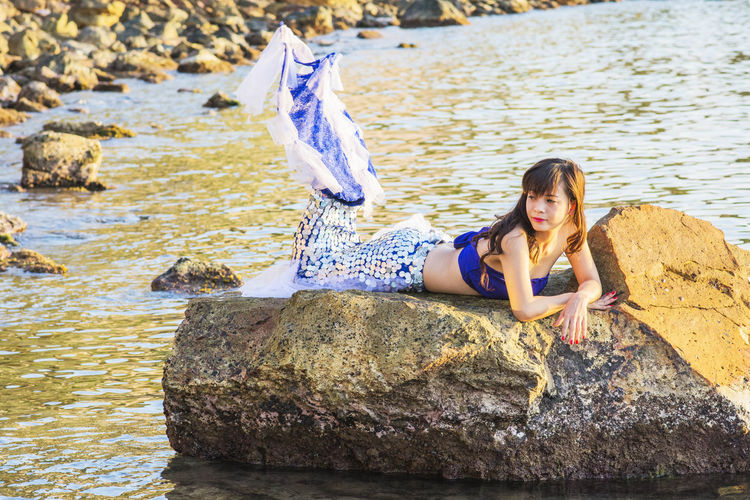 Portrait of young woman on rocks at shore