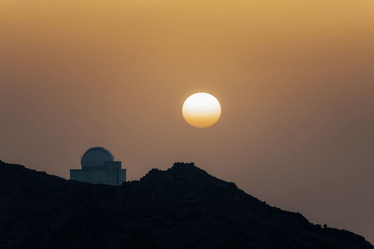 Low angle view of observatory against orange sunset