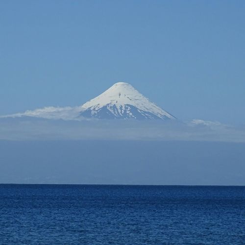 Scenic view of snowcapped mountains by sea against clear sky