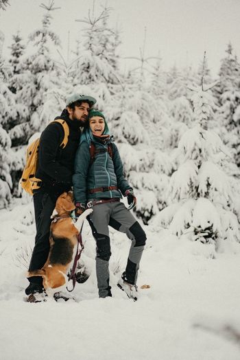 Couple in love walking on snow covered land with their dog