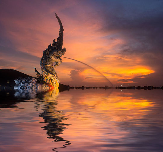 Naga statue by songkhla lake against sky at dusk