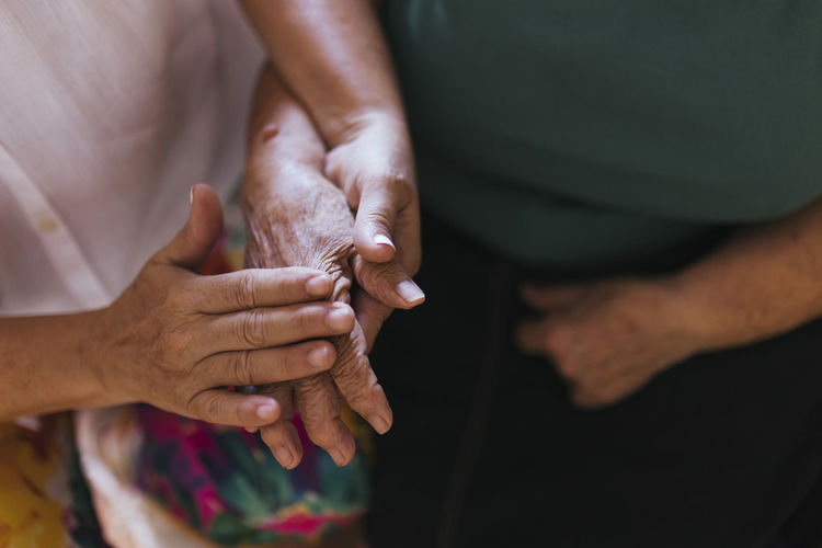 Woman caressing hand of elderly mother