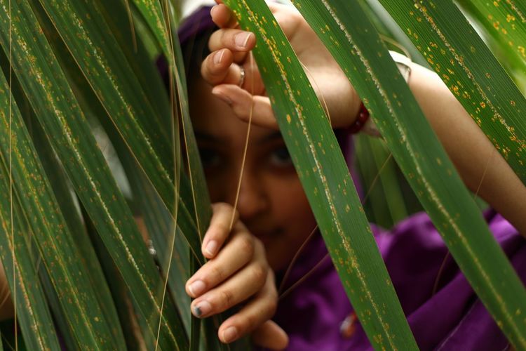 Portrait of young woman looking through leaves
