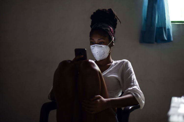 Young woman in face mask using smartphone